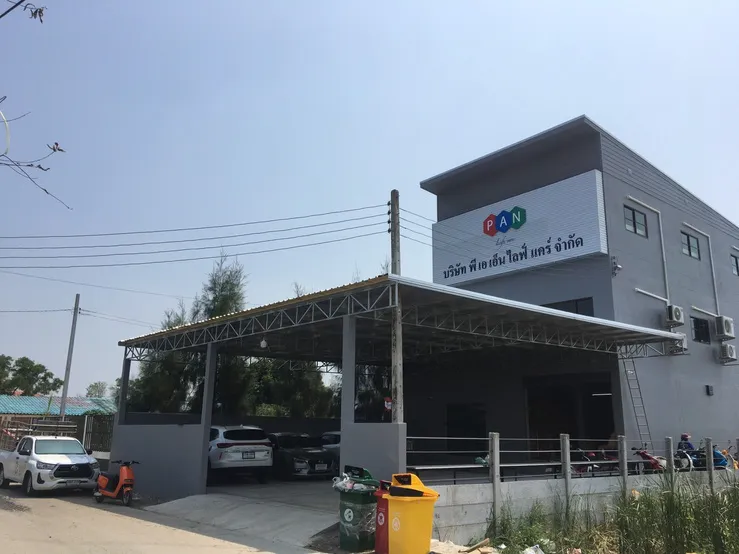 PAN Lifecare Building, Nong Chok: a two-storey grey office with the PAN Life care sign and a covered car park in front
